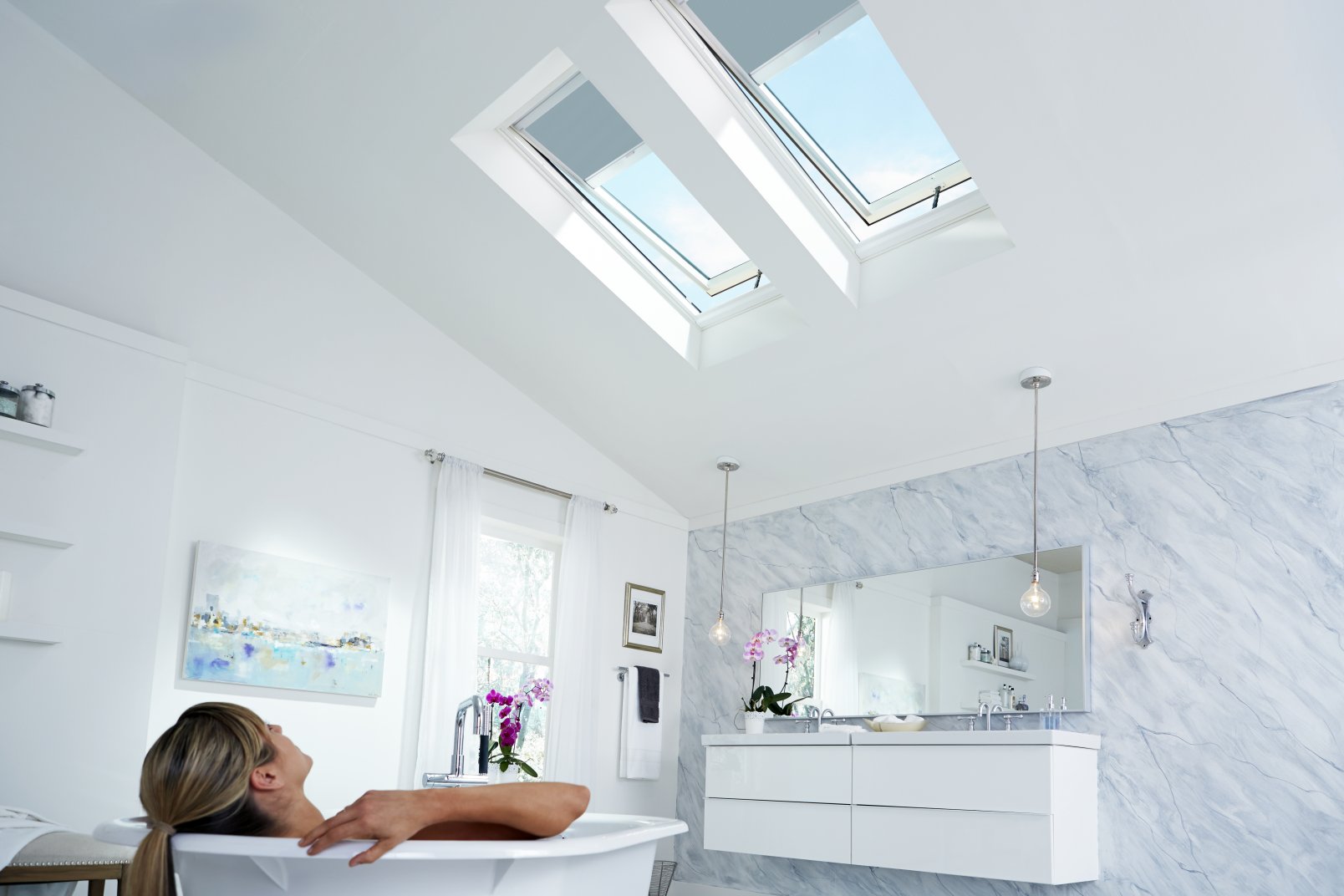 woman in bathtub with skylights and blinds half way closed in auckland